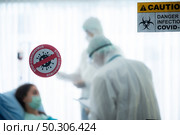 virus control experts doctor in PPE suit working for disease treatment with coronavirus COVID-19 infected patient people in hospital quarantine negative pressure room, outbreak alert sign. Стоковое фото, агентство Ingram Publishing / Фотобанк Лори