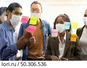 Interracial asian business team brainstorming idea at office meeting room after reopen due to coronavirus COVID-19 city lockdown. They wear face mask reduce risk to infection as new normal lifestyle. Стоковое фото, агентство Ingram Publishing / Фотобанк Лори