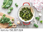 Sauteed kale with garlic in cast iron pan on kitchen table, healthy food concept, superfood. Стоковое фото, агентство Ingram Publishing / Фотобанк Лори