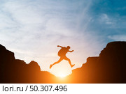 Man jump through gaps between hills. Стоковое фото, агентство Ingram Publishing / Фотобанк Лори