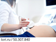 Cropped close up of an ultrasound scanner in hands of doctor examining her pregnant patient copyspace technology modern medicine healthcare pregnancy diagnosing sonogram unborn motherhood concept.. Doctor performing ultrasound scanning for her pregnant patient. Стоковое фото, агентство Ingram Publishing / Фотобанк Лори