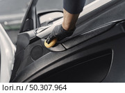 Man in a garage. Worker polish inside a car. Man in a black uniform. Стоковое фото, агентство Ingram Publishing / Фотобанк Лори