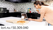 Panoramic Asian woman work from home in the kitchen and eating delivery pizza take away food and take out coffee while city lockdown from coronavirus covid-19 pandemic. New Normal lifestyle. Стоковое фото, агентство Ingram Publishing / Фотобанк Лори