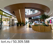 The interior of a luxury shopping mall with an escalator, a coffee shop, luxury shops and advertising signs. Russia. Moscow. 22.06.25. Редакционное фото, фотограф Ярославский Максим / Фотобанк Лори