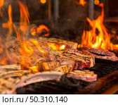 Overcooked meat steaks into flames on the grill. Стоковое фото, агентство Ingram Publishing / Фотобанк Лори