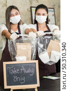 Close up waitress wear protective face mask smile and hold shopping bag for take away or takeout food. This essential service is very popular while city lockdown from coronavirus COVID-19 Pandemic. Стоковое фото, агентство Ingram Publishing / Фотобанк Лори