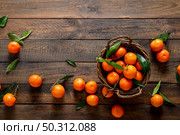 Tangerines, fresh mandarin oranges, clementines with leaves on wooden background. Top view, copy space. Стоковое фото, агентство Ingram Publishing / Фотобанк Лори