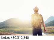 Young Man Traveler with backpack relaxing outdoor. Summer vacations and Lifestyle hiking concept. Retro filter effect, selective focus. Стоковое фото, агентство Ingram Publishing / Фотобанк Лори