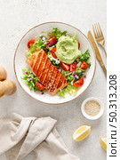 Grilled salmon fish fillet and fresh green lettuce vegetable tomato salad with avocado guacamole. Top view. Стоковое фото, агентство Ingram Publishing / Фотобанк Лори