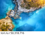 Aerial view of floating board and people on blue sea, rocks with trees at sunset in summer in Blue lagoon, Oludeniz, Turkey. Tropical landscape. Kayaks on clear water. Active travel. Top view of canoe. Стоковое фото, агентство Ingram Publishing / Фотобанк Лори