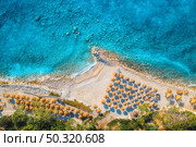 Aerial view of sandy beach with umbrellas, green forest at sunset in summer. Blue lagoon in Oludeniz, Turkey. Tropical landscape with sea bay, island, white sandy bank, blue water. Top view. Nature. Стоковое фото, агентство Ingram Publishing / Фотобанк Лори