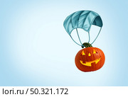 Halloween medical recovery with a facial mask being used as a parachute as a jack o lantern pumpkin as an autumn symbol for disease control and virus infection and coronavirus or covid-19 safety in a 3D illustration style. Стоковое фото, агентство Ingram Publishing / Фотобанк Лори