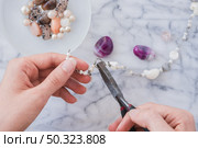 close up woman s hand fixing bracelet with plier marble desk. Стоковое фото, агентство Ingram Publishing / Фотобанк Лори