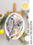 Fresh whole dorada fish and ingredients for cooking. Raw sea bream with spices on white background. Healthy food, diet. Top view with copy space. Стоковое фото, агентство Ingram Publishing / Фотобанк Лори