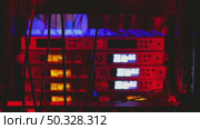 A server rack illuminated in blue hues, showcasing multiple electronic devices. Twisted cables partially obscure the view of the equipment, emphasizing a high-tech environment. Стоковое видео, видеограф Воловодов Владимир / Фотобанк Лори