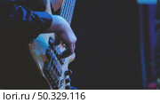 Close-up of skillful bass guitar playing during a live concert. Dark background enhances the focus on the instrument and the performer's technique, while soft blue lighting emphasizes the scene. Стоковое видео, видеограф Воловодов Владимир / Фотобанк Лори
