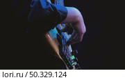 Close-up of a bassist's hand, playing bass guitar professionally, illuminated by soft multicolored stage lights against a dark background. Fingers skillfully plucking the strings. Стоковое видео, видеограф Воловодов Владимир / Фотобанк Лори