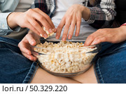bowl with popcorn hands girl sitting cross legged sofa. High resolution photo. bowl with popcorn hands girl sitting cross legged sofa. High quality photo. Стоковое фото, агентство Ingram Publishing / Фотобанк Лори