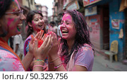 People covered in vibrant colors laughing and celebrating the Holi festival together on a bustling street. Стоковое AI-изображение, AI-художник Данила Большаков / Фотобанк Лори