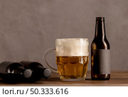 glass beer with foam brown bottles beer wooden table. Стоковое фото, агентство Ingram Publishing / Фотобанк Лори