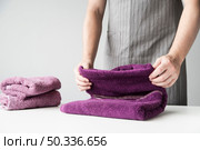 front view person folding towels. Стоковое фото, агентство Ingram Publishing / Фотобанк Лори