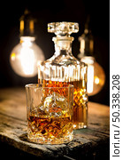 Glass of whiskey and decanter on wooden table. Стоковое фото, агентство Ingram Publishing / Фотобанк Лори