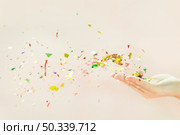 confetti blowing from hands against beige background. Стоковое фото, агентство Ingram Publishing / Фотобанк Лори