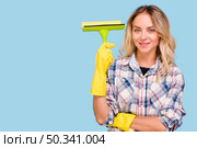 young smiling woman holding plastic wiper looking camera against blue background. Стоковое фото, агентство Ingram Publishing / Фотобанк Лори