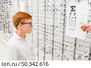 boy with spectacle looking snellen chart while doctor s hand pointing chart. Стоковое фото, агентство Ingram Publishing / Фотобанк Лори