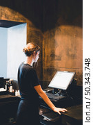 young hostess standing near cash register. Стоковое фото, агентство Ingram Publishing / Фотобанк Лори