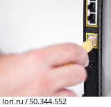 OLYMPUS DIGITAL CAMERA. hand plugging ethernet cable into router. Стоковое фото, агентство Ingram Publishing / Фотобанк Лори