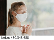 little girl with medical mask praying. Стоковое фото, агентство Ingram Publishing / Фотобанк Лори