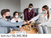 people office during pandemic having meeting fist bumping each other. Стоковое фото, агентство Ingram Publishing / Фотобанк Лори