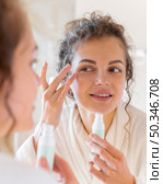 woman applying cream face while looking mirror. Стоковое фото, агентство Ingram Publishing / Фотобанк Лори