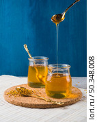 OLYMPUS DIGITAL CAMERA. honey dripping from spoon pot bee pollens cork coaster. Стоковое фото, агентство Ingram Publishing / Фотобанк Лори