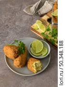 Cod dumplings, or "bolinhos de bacalhau" and parsley leaves and lemons on wooden cutting board in a kitchen counter top. Стоковое фото, агентство Ingram Publishing / Фотобанк Лори
