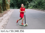 little girl riding push scooter road. Стоковое фото, агентство Ingram Publishing / Фотобанк Лори