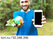 man holding globe with leaf smartphone. Стоковое фото, агентство Ingram Publishing / Фотобанк Лори
