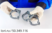 A technician in blue uniform and protective gloves holds three grey plastic pipe clamps. Стоковое фото, фотограф Анастасия / Фотобанк Лори