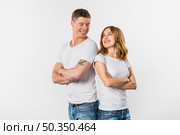 smiling young couple standing back back looking each other against white background. Стоковое фото, агентство Ingram Publishing / Фотобанк Лори