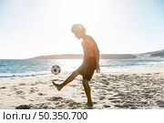 young sportsman tossing up ball seacoast. Стоковое фото, агентство Ingram Publishing / Фотобанк Лори