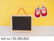 baby concept with slate shoes hanging clothesline. Стоковое фото, агентство Ingram Publishing / Фотобанк Лори