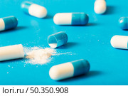 broken capsule with white powder blue background. Стоковое фото, агентство Ingram Publishing / Фотобанк Лори