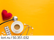 coffee cup blister packed tablets stethoscope stitched heart shape against yellow background. Стоковое фото, агентство Ingram Publishing / Фотобанк Лори