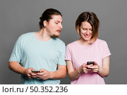 young man spying peeking smartphone her girlfriend using mobile phone. Стоковое фото, агентство Ingram Publishing / Фотобанк Лори
