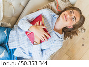 smiling young woman lying sofa with book. Стоковое фото, агентство Ingram Publishing / Фотобанк Лори