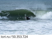 Bodyboarder performing a tube trick surfing ocean wavesurfing ocean wave on a cloudy winter day. Стоковое фото, агентство Ingram Publishing / Фотобанк Лори