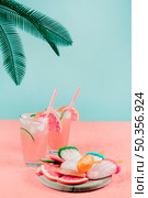 palm leaves grapefruit cocktail glasses popsicles coral desk against teal background. Стоковое фото, агентство Ingram Publishing / Фотобанк Лори