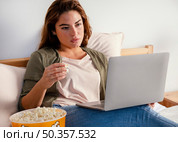 woman eating popcorn while watching movie laptop. Стоковое фото, агентство Ingram Publishing / Фотобанк Лори