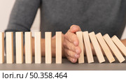 domino made with wooden pieces representing finances struggles. Стоковое фото, агентство Ingram Publishing / Фотобанк Лори